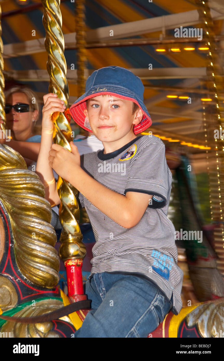 A young boy rides on The Victorian Gallopers Roundabout carousel at Bressingham museum in Norfolk Uk Stock Photo