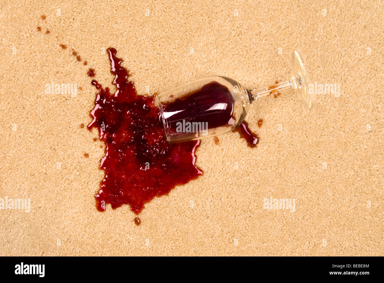 A glass of spilled wine on brand new carpet will leave a stain. Stock Photo