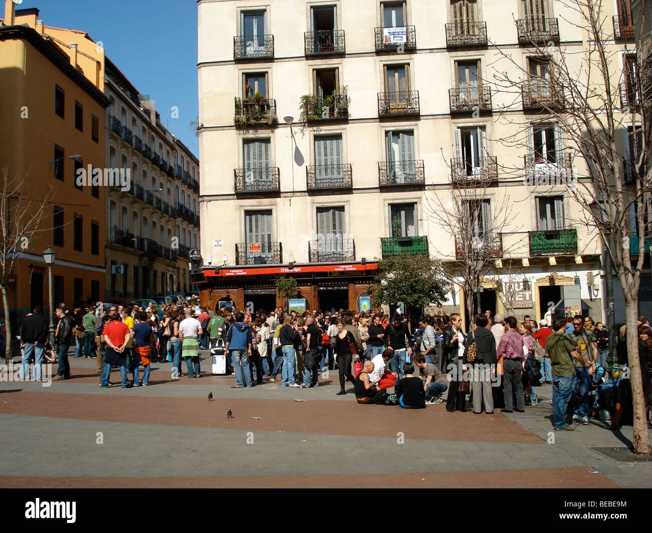 A young affluent crowd drink in the afternoon sun, in Chueca the gay district of Madrid. Plaza de Chueca, Madrid, Spain. Stock Photo