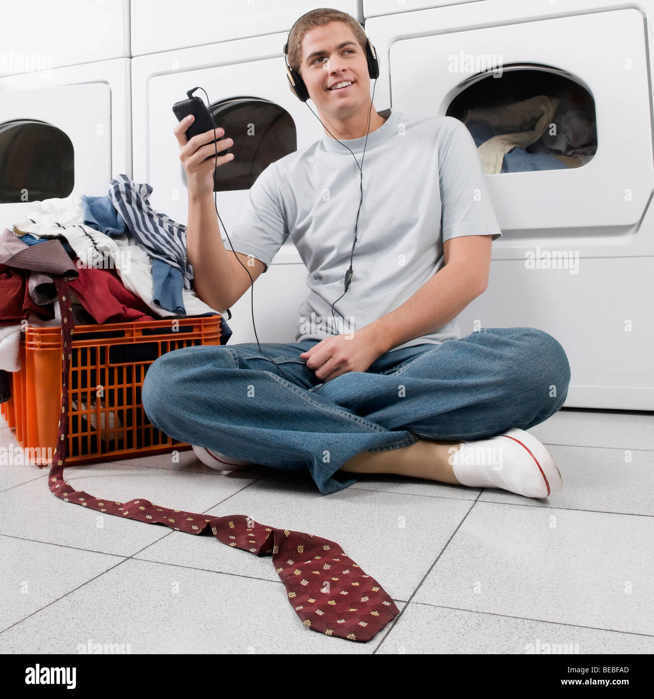 Man listening to an MP3 player in a laundromat Stock Photo