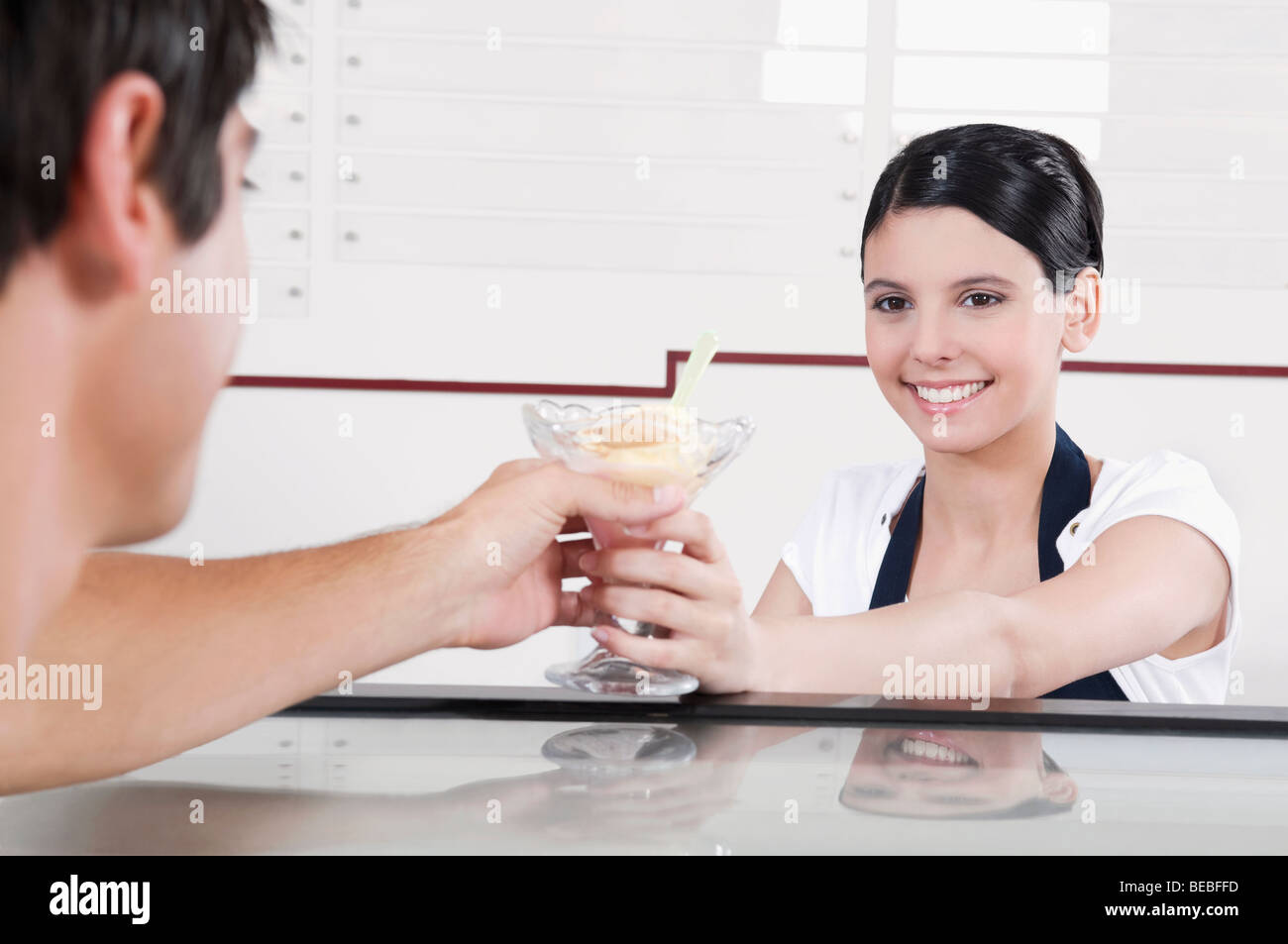 Female ice cream seller giving ice cream to a customer Stock Photo