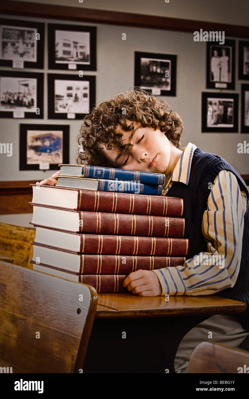 Schoolboy sleeping on a stack of books in a classroom Stock Photo - Alamy