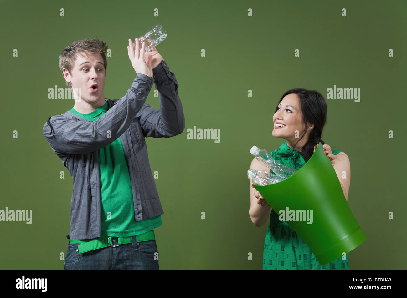 Woman holding a recycling bin and a man looking into an empty water bottle Stock Photo