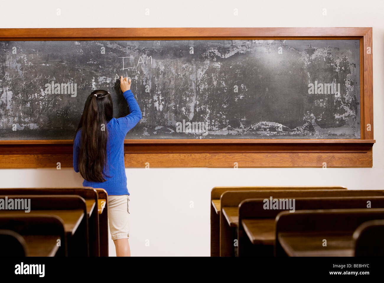 Schoolgirl writing on a blackboard in a classroom Stock Photo