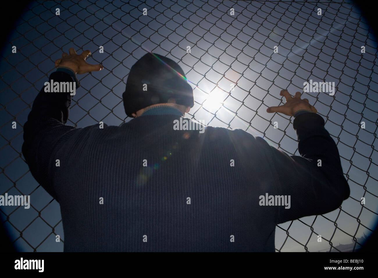 Prisoner clinging to a chainlink fence Stock Photo