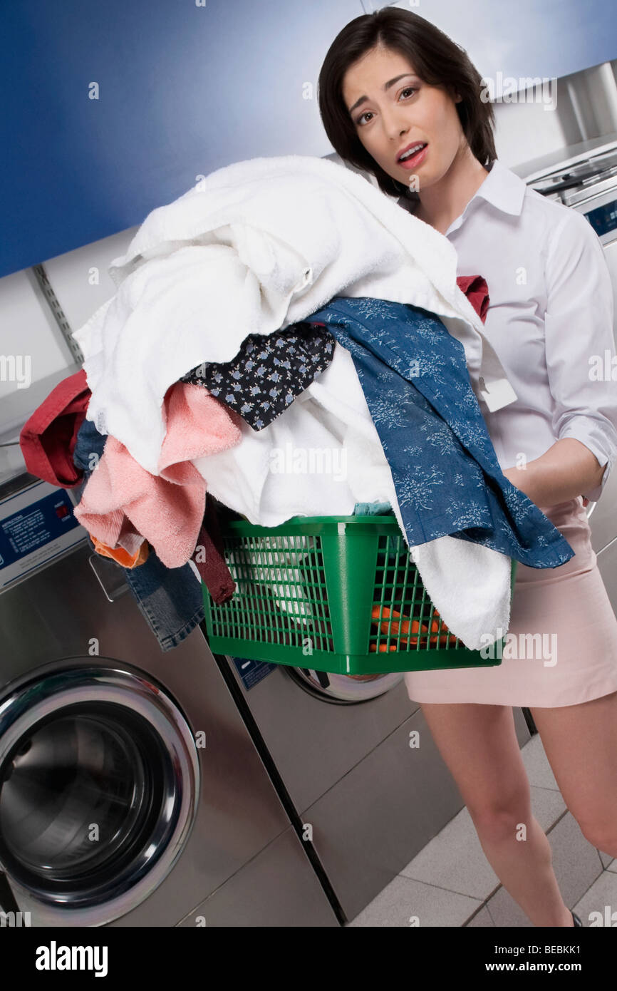 Woman carrying a laundry basket in a laundromat Stock Photo Alamy