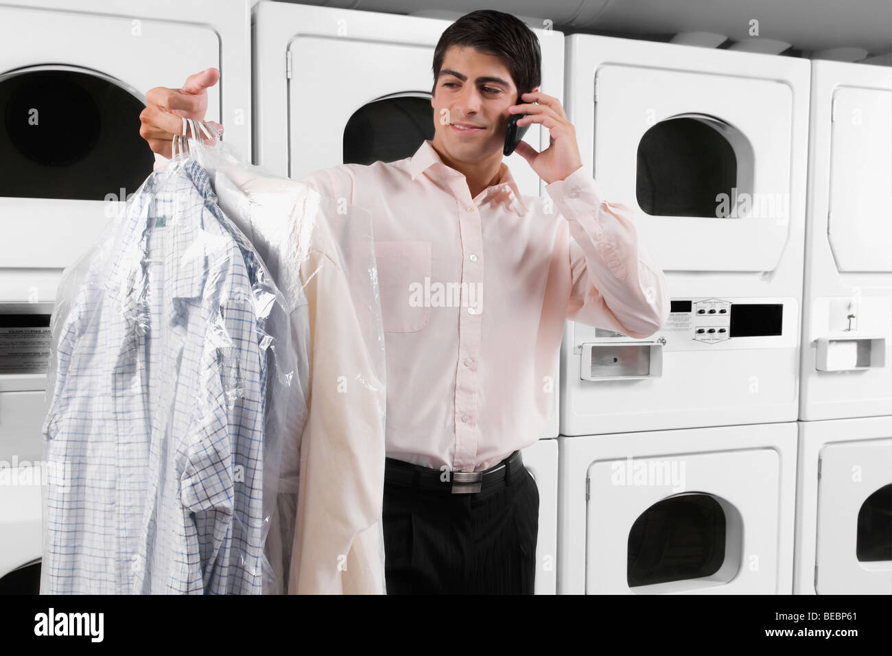Man talking on a mobile phone and holding shirts Stock Photo
