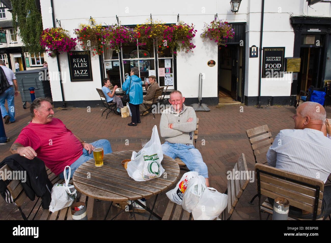 People sat drinking on sunny afternoon outside Hen and chickens pub at Abergavenny Monmouthshire South Wales UK Stock Photo