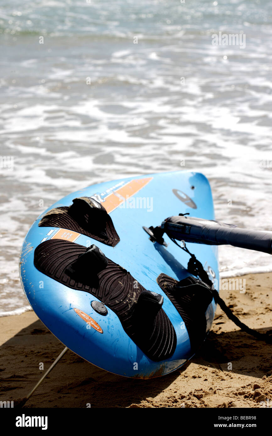 Colourful Windsurfing Boards And Sails Laying On A Sandy Beach Waiting