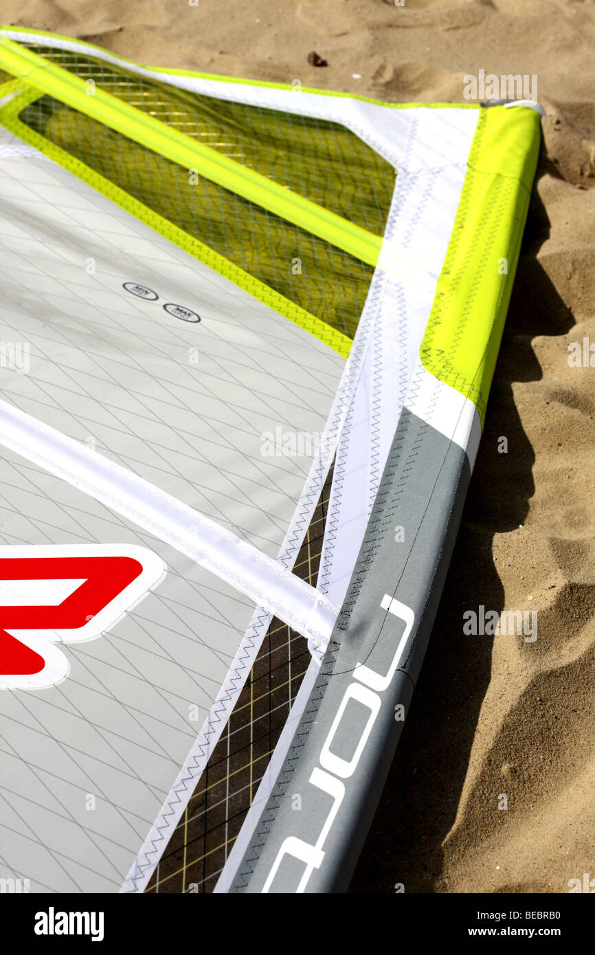 Colourful Windsurfing Boards And Sails Laying On A Sandy Beach Waiting