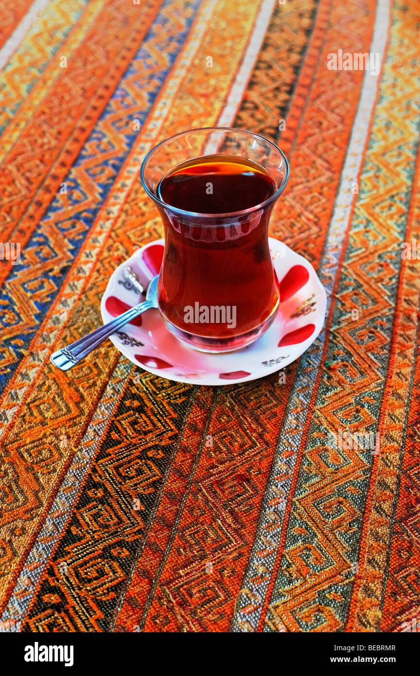 Turkish Tea (cay), served on traditional fabric tablecloth in tulip shaped glass. Stock Photo