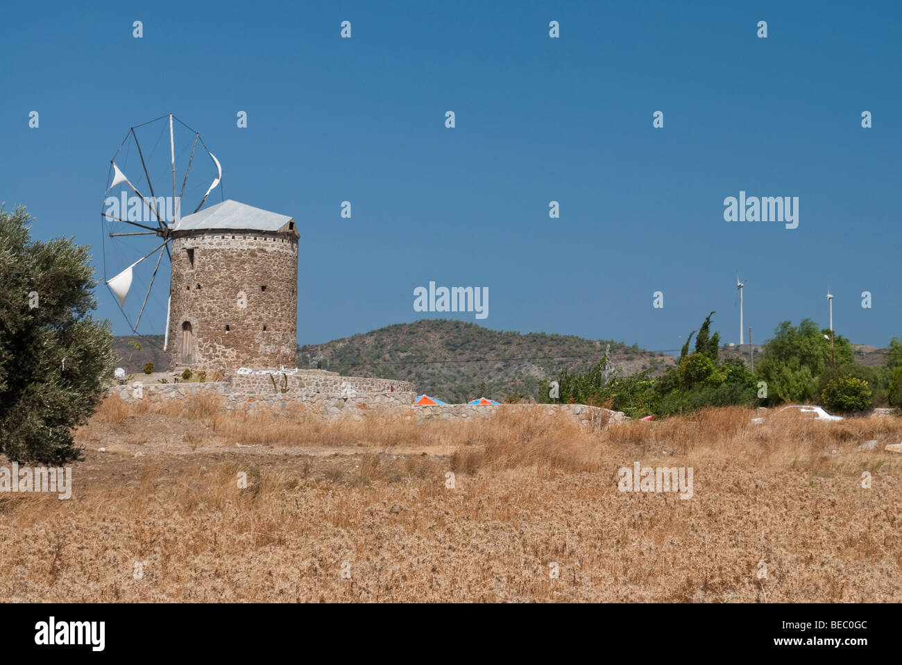 Old windmill with new wind turbines in the background on the Datca peninsula, near Marmaris, Turkey Stock Photo
