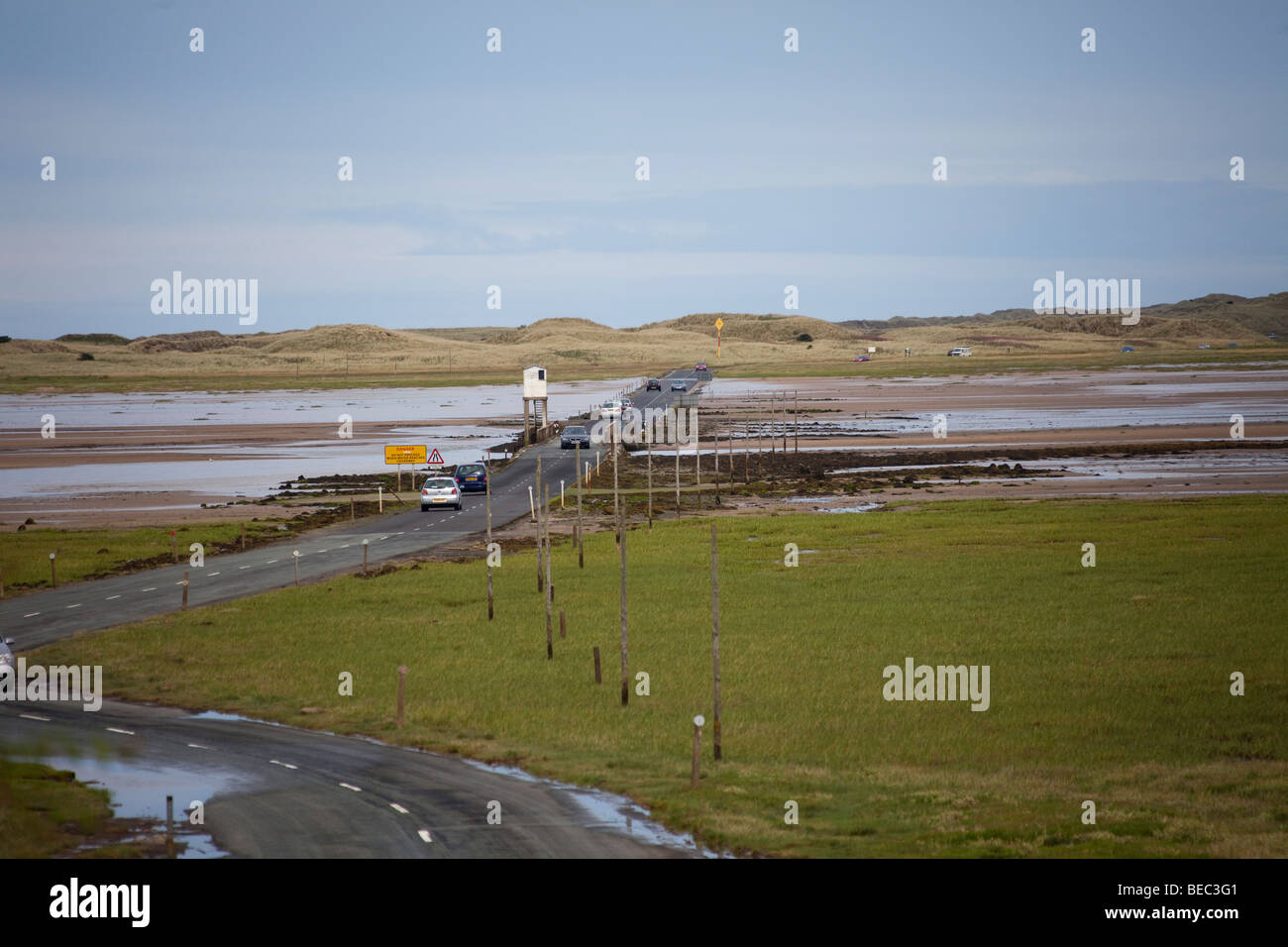 Causeway tide road path with cars at Lindisfarne Holy Island UK Northumberland.96947 Holy Island Causeway Stock Photo