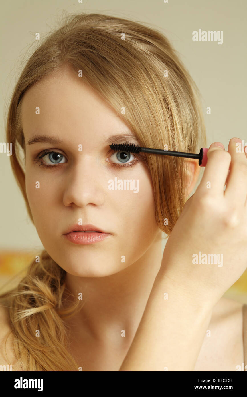 Teenage girl applying mascara onto eyelashes. Stock Photo