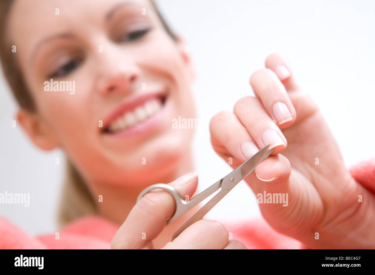 Young woman is cutting nails with scissors. Stock Photo