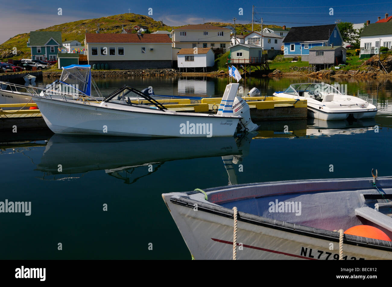 White cross on hill overlooking harbour boats and village houses of
