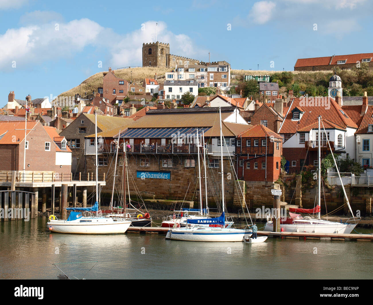 Sailing boats at the private moorings of the Whitby Yacht Club with houses and St Marys Church behind Stock Photo