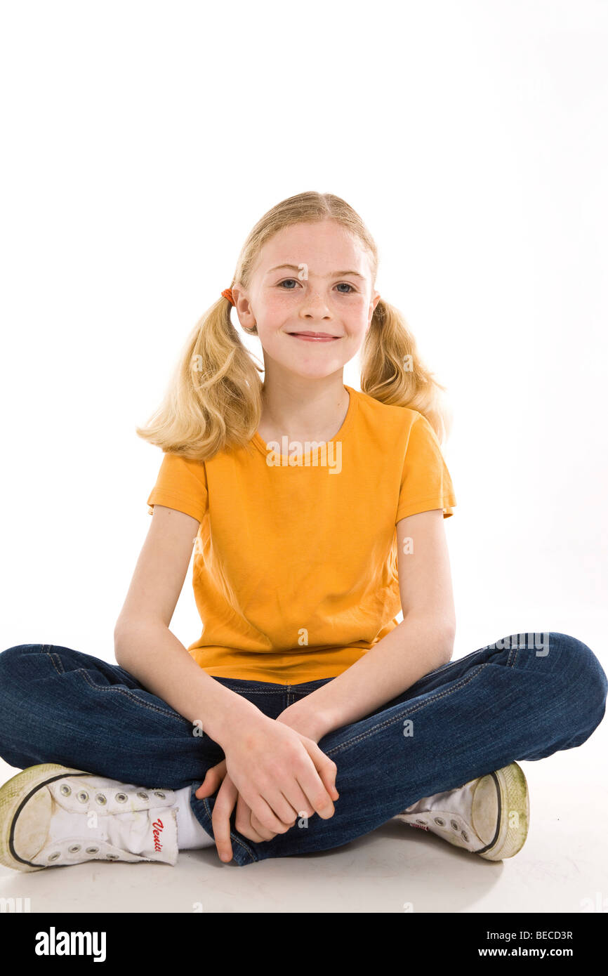 A smiling, blonde girl sitting with crossed legs Stock Photo - Alamy