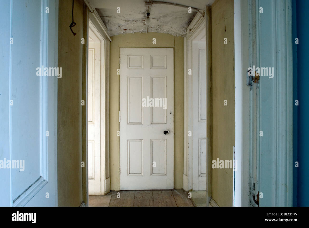 corridor leading up to a white door with other doorways off it in an old stately manor home in england Stock Photo