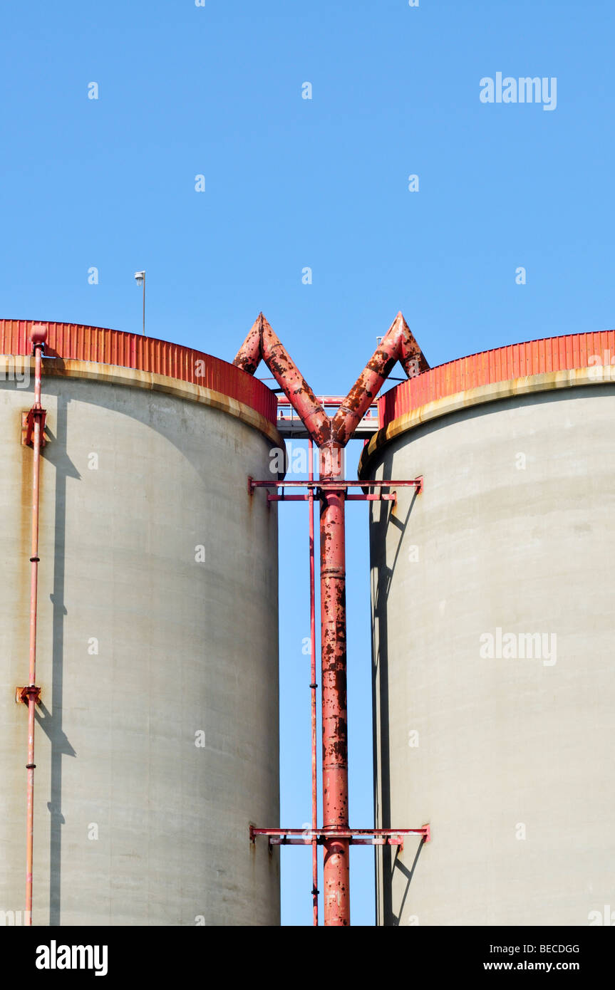 Industrial concept with pipe joining two cement silos Stock Photo