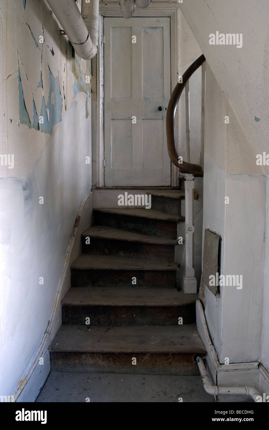 white staircase and door in derelict building with paint falling off the wall Stock Photo