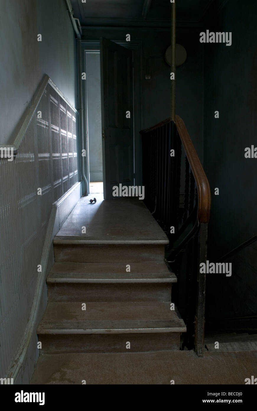 staircase leading up to a brightly lit room in abandoned house with door handle lying on the floor Stock Photo