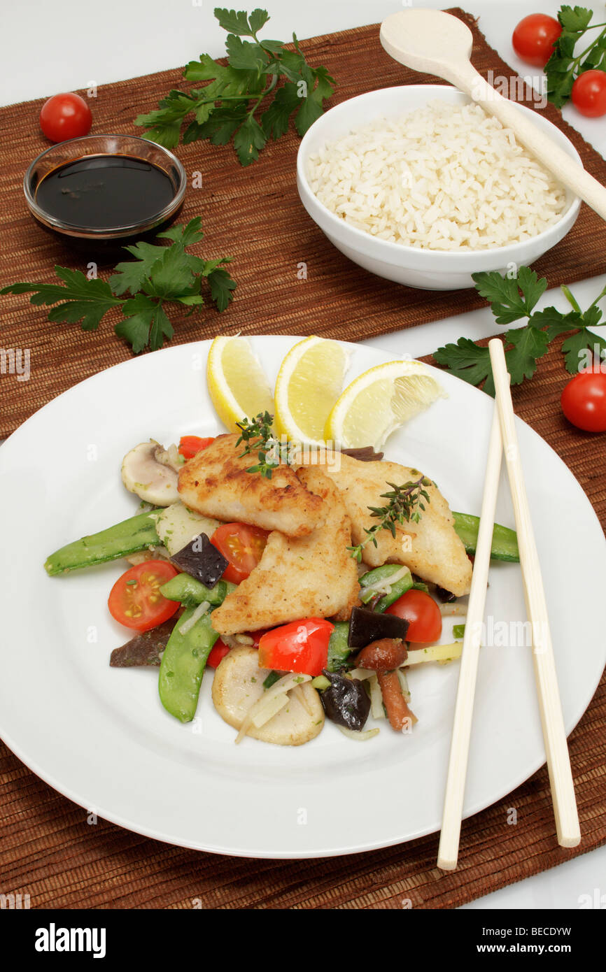 Pangasius filet on a bed of Asian vegetables with sweet soy sauce and rice Stock Photo
