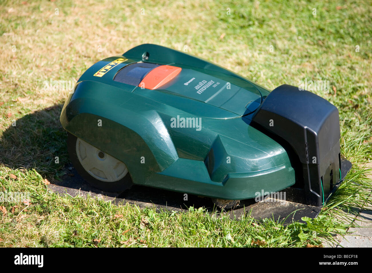 Green automatic robot lawnmower docked in its charging station, top view Stock Photo
