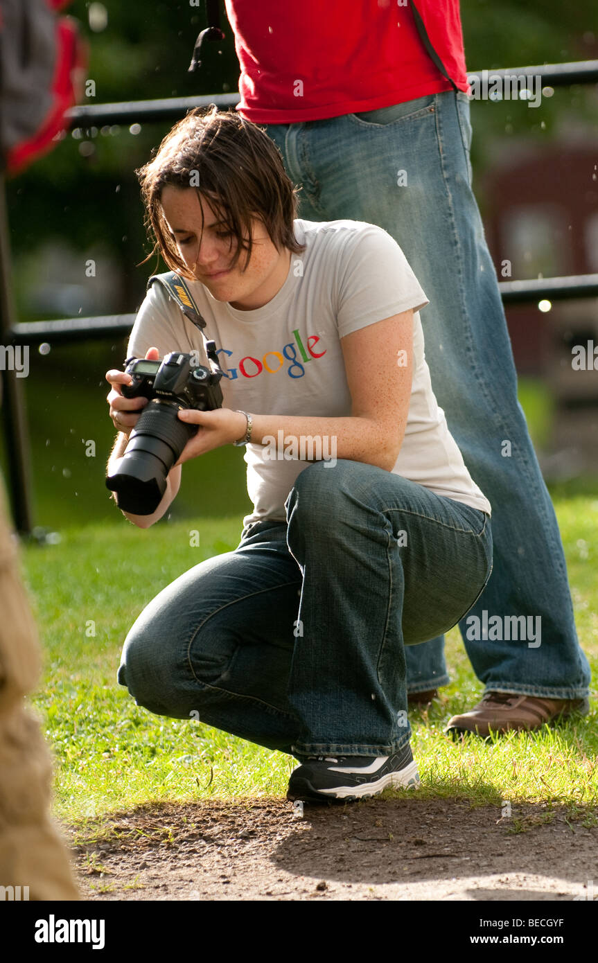 A young female photographer reviews images during a downpour. Stock Photo
