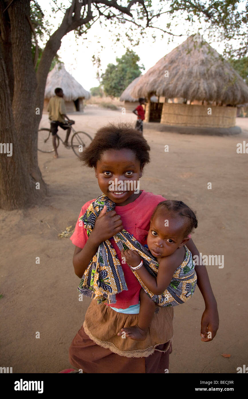 Child carrying an infant in a cloth, Kawaza village, Eastern Province, Republic of Zambia, Africa Stock Photo