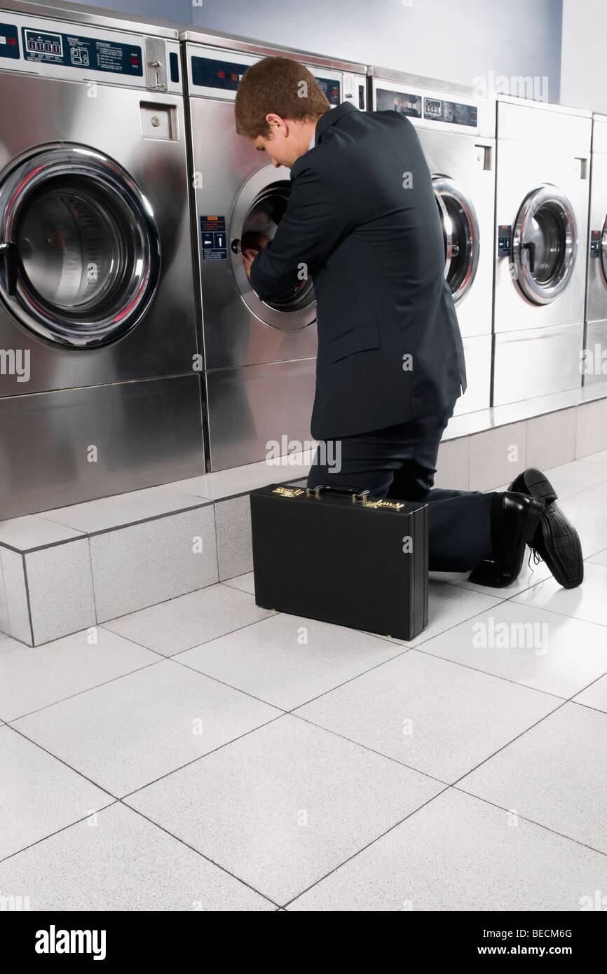 Businessman putting clothes into a washing machine Stock Photo