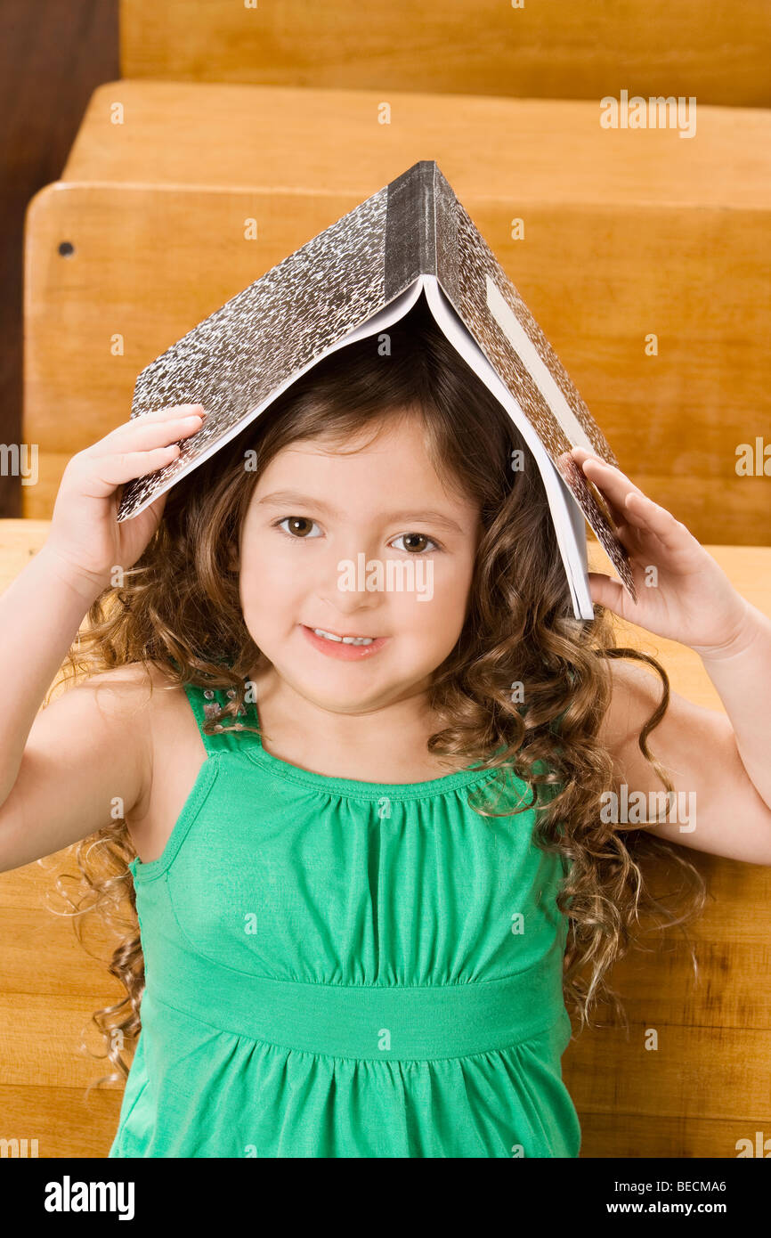 Schoolgirl holding a book on her head in a classroom Stock Photo - Alamy