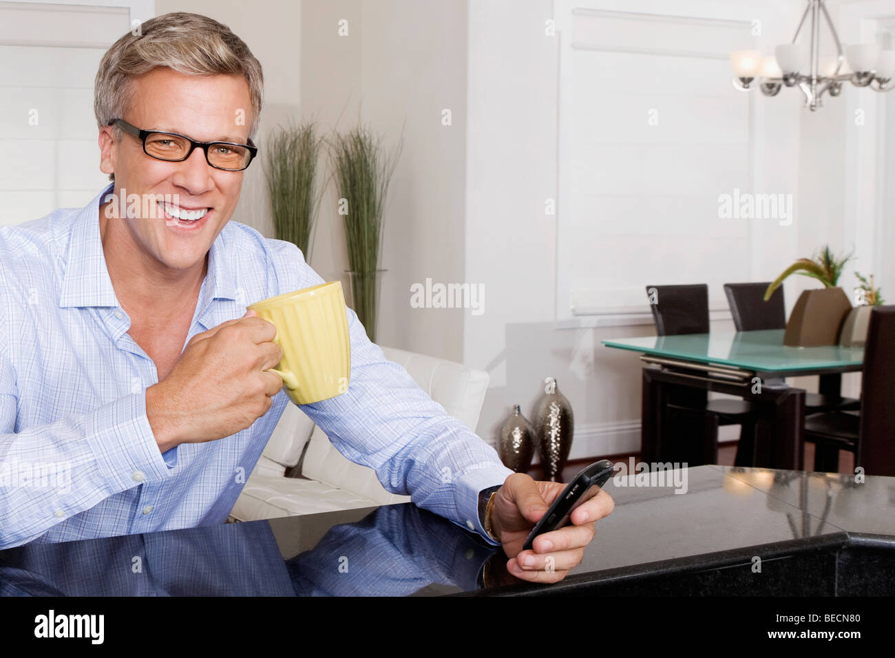 Man drinking coffee and text messaging on a mobile phone Stock Photo