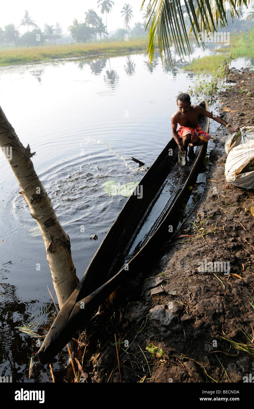 Farmer bailing out rainwater from his vallam wooden canoe in the Backwaters, Kerala, India Stock Photo