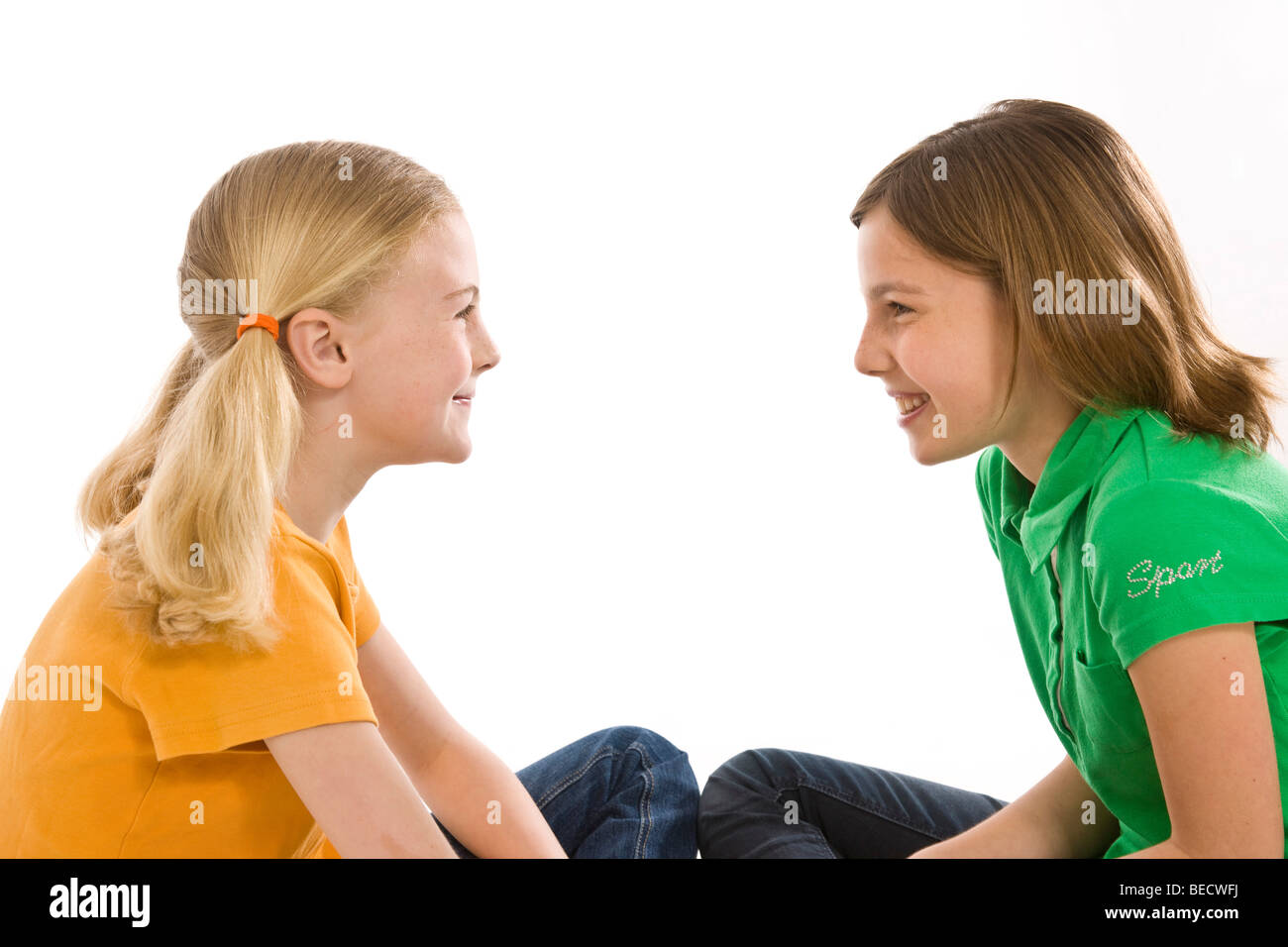 Two girls sitting on the floor, smiling at each other Stock Photo - Alamy