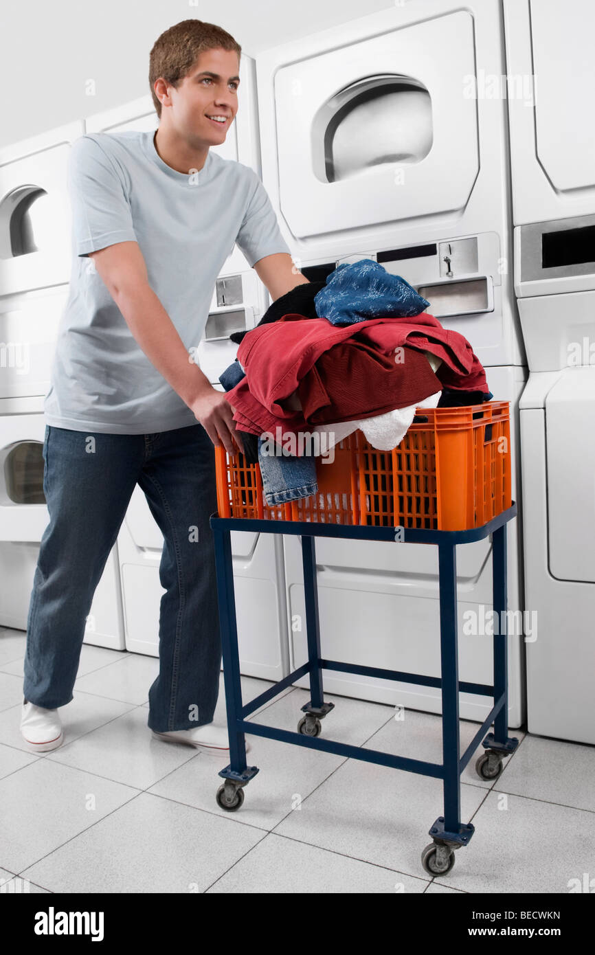 Man pushing a laundry basket in a laundromat Stock Photo