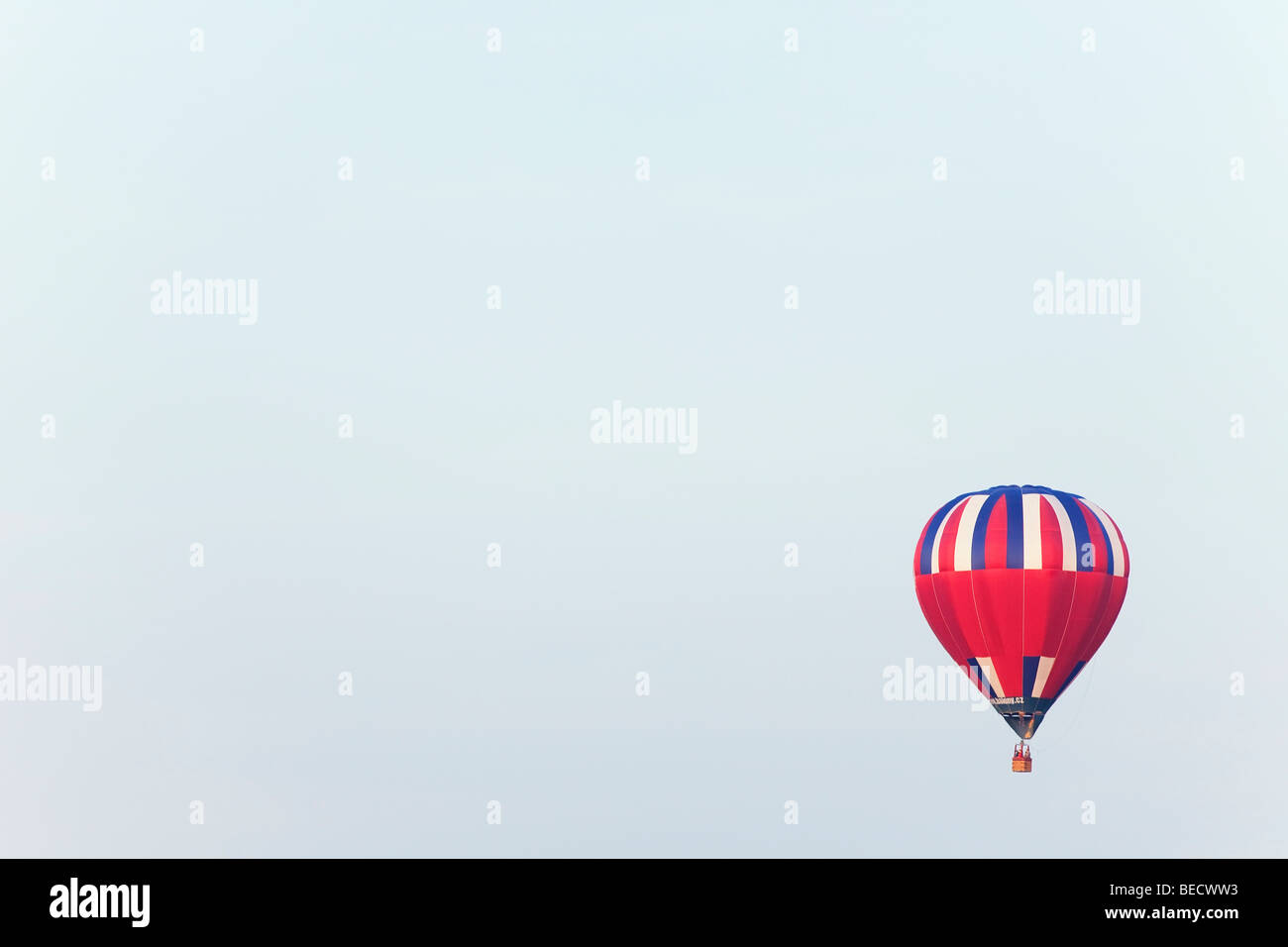 A vibrant hot air balloon floats serenely against a clear blue sky ...