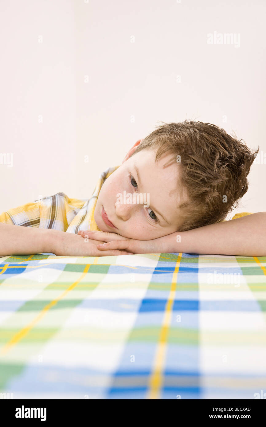Boy sitting at a table, bored Stock Photo