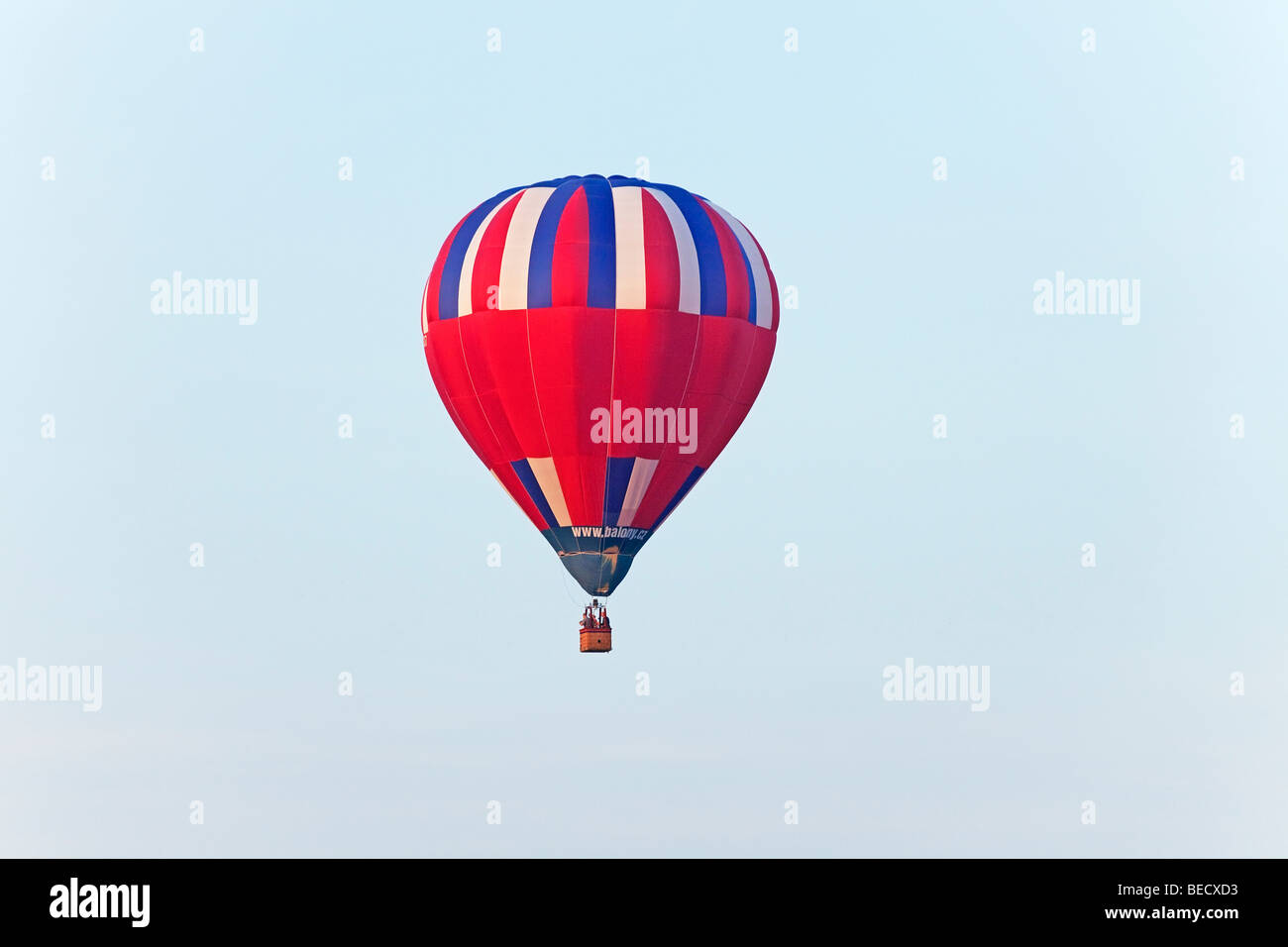 A vibrant hot air balloon floats serenely against a clear blue sky ...