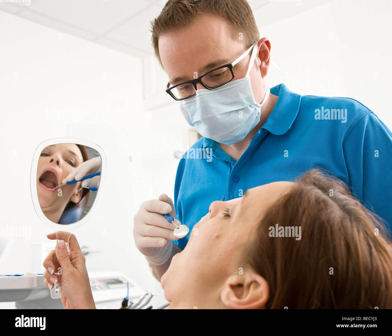 Patient looking into a hand mirror during a dental check Stock Photo