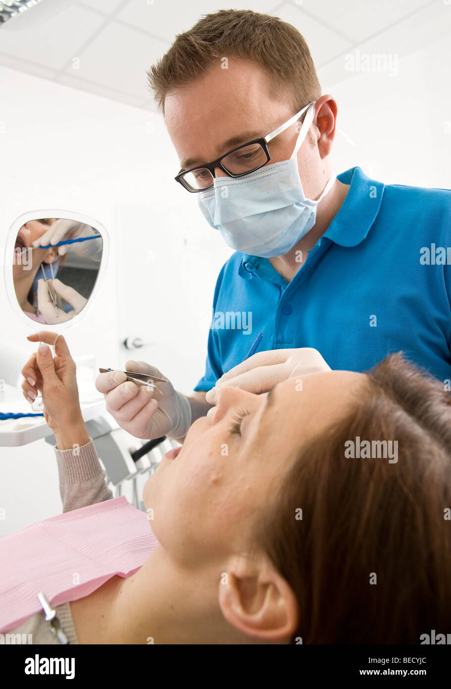 Patient looking into a hand mirror during a dental check Stock Photo