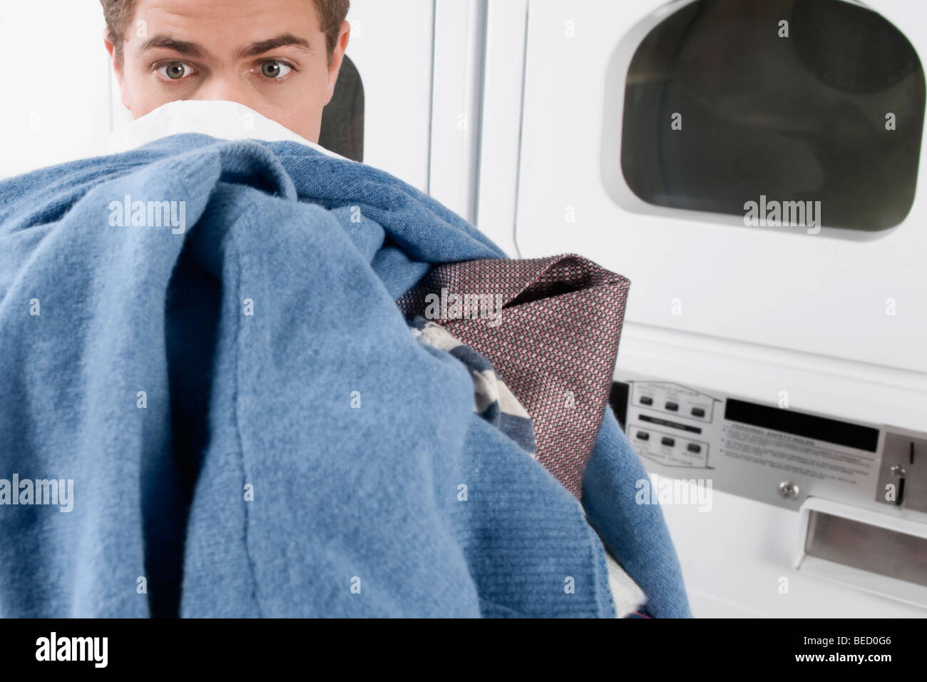 Man carrying clothes in a laundromat Stock Photo