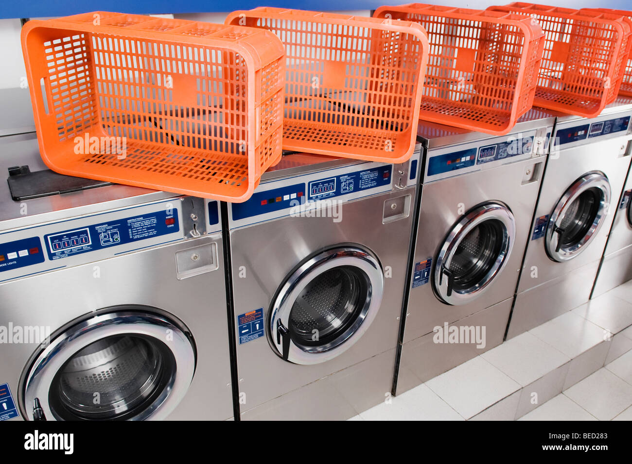 Laundry baskets on washing machines in a laundromat Stock Photo Alamy