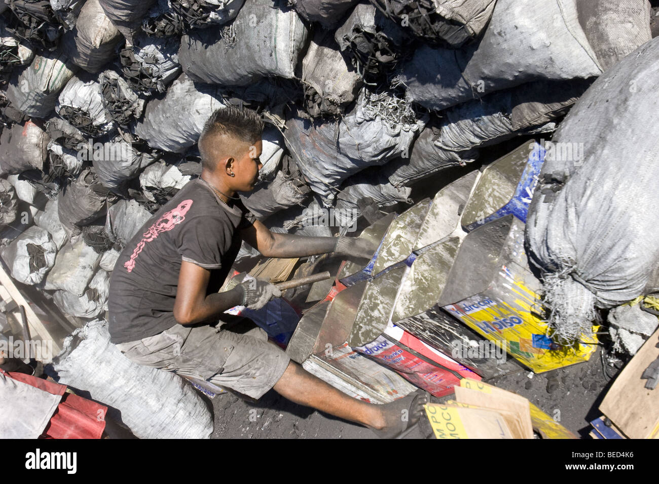 a charcoal seller breaks apart large chunks of charcoal into small briquettes for cooking the traditional churrasco in Brazil Stock Photo