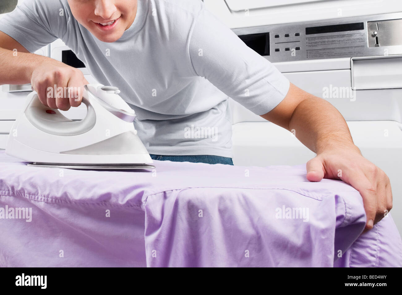 Man ironing in a laundromat Stock Photo