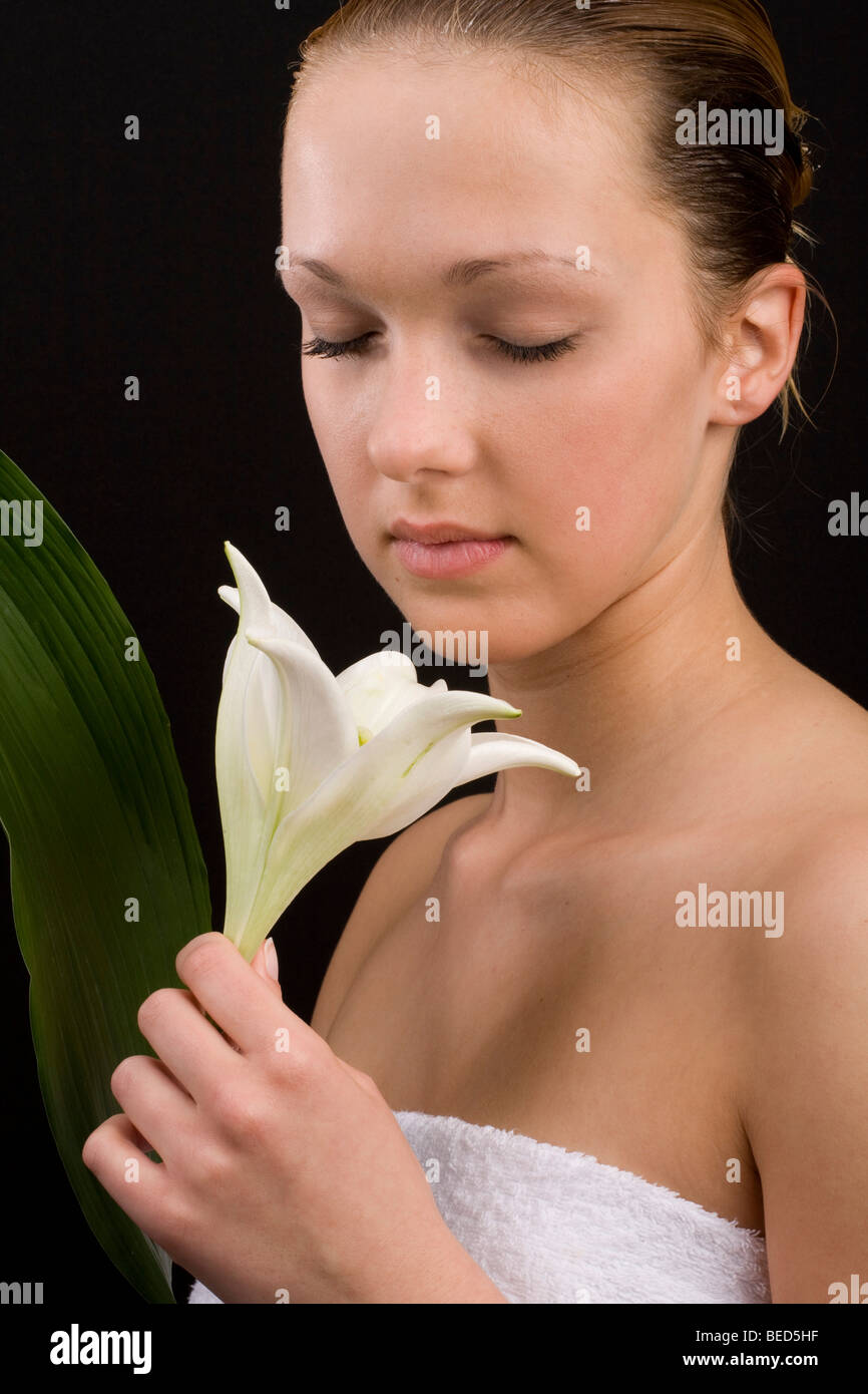 Woman wrapped in a towel, smelling a lily Stock Photo