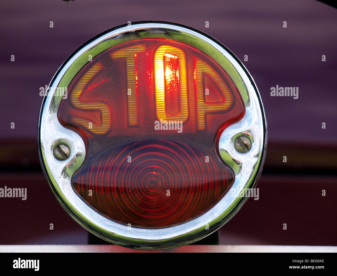 illuminated stoplight with lit up word STOP in chrome fitting on dark