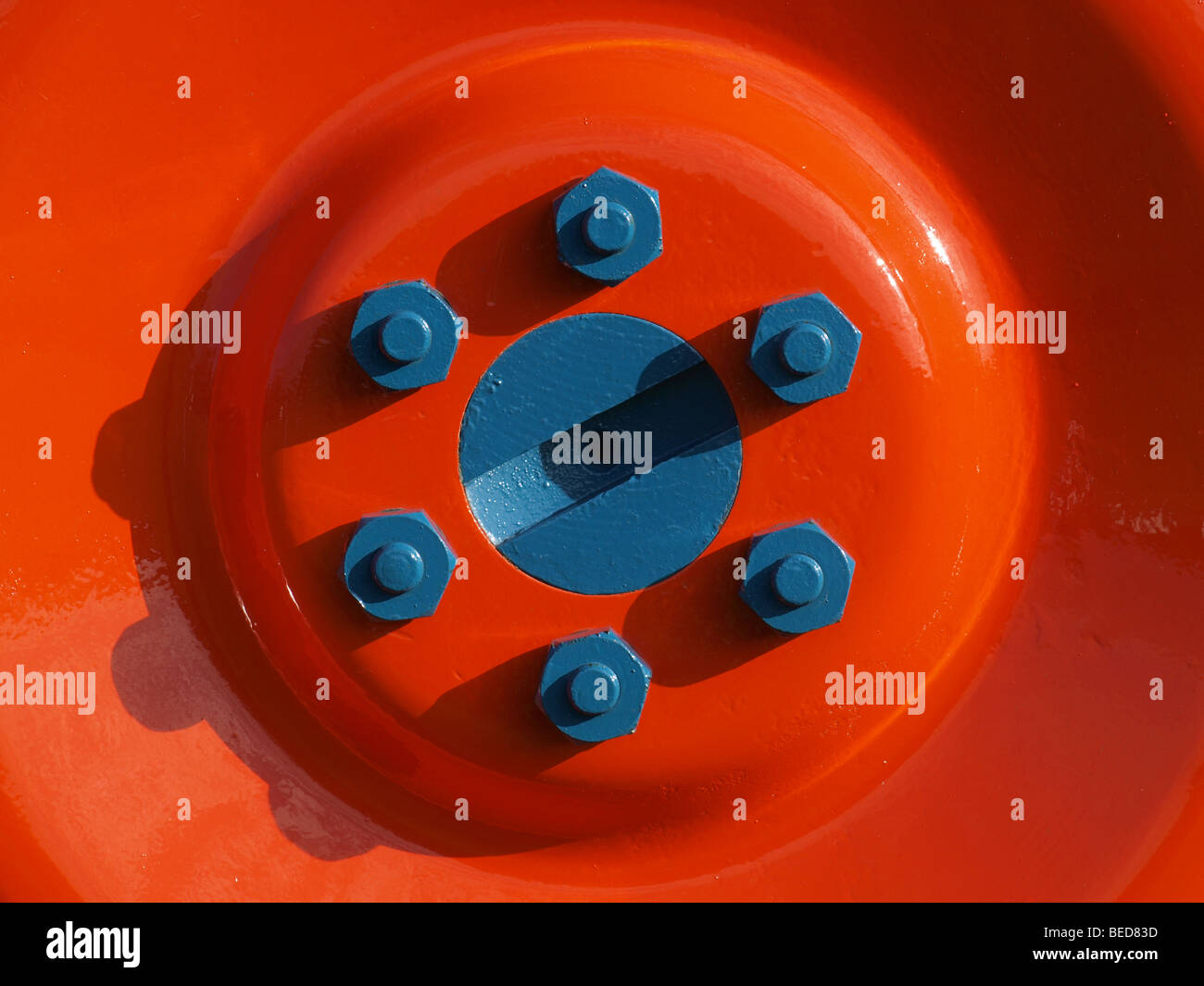 bright tractor wheel hub in oblique sunshine casts shadows from 6 wheel nuts Stock Photo