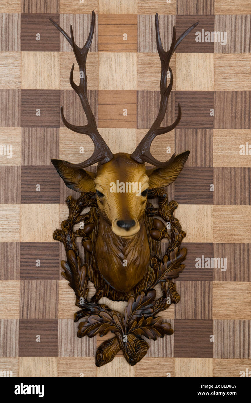 Plastic deer head mounted on imitation wood wallpaper, frontal view Stock Photo