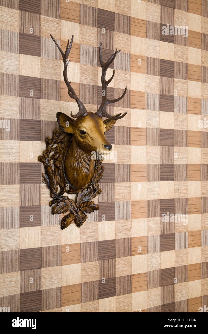 Plastic deer head mounted on imitation wood wallpaper, side view Stock Photo